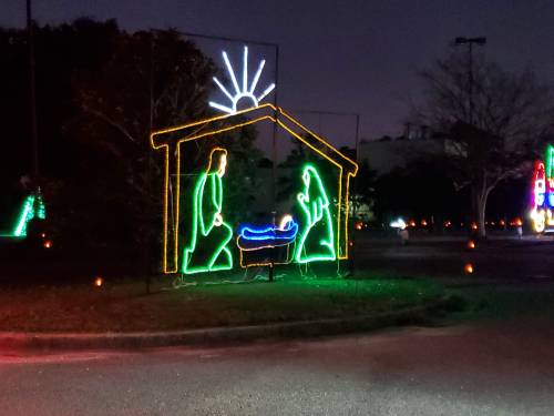 A colorful light display depicting a nativity scene with Mary, Joseph, and baby Jesus in a stable.