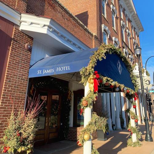Exterior of St. James Hotel with festive decorations and a blue awning, showcasing brick architecture and greenery.