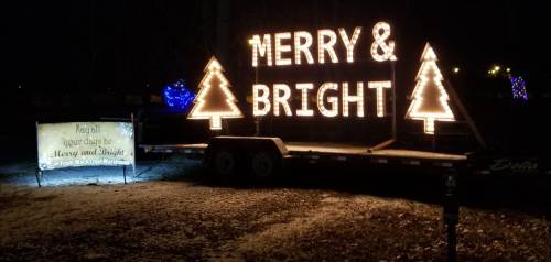 A festive display reads "MERRY & BRIGHT" in lights, with two illuminated Christmas trees beside it.