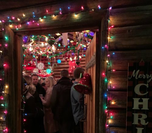 A festive entrance to a cozy, crowded space decorated with colorful Christmas lights and ornaments.
