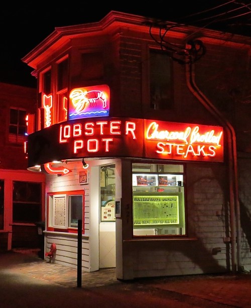 A brightly lit restaurant sign reading "Lobster Pot" and "Charcoal Broiled Steaks" at night.