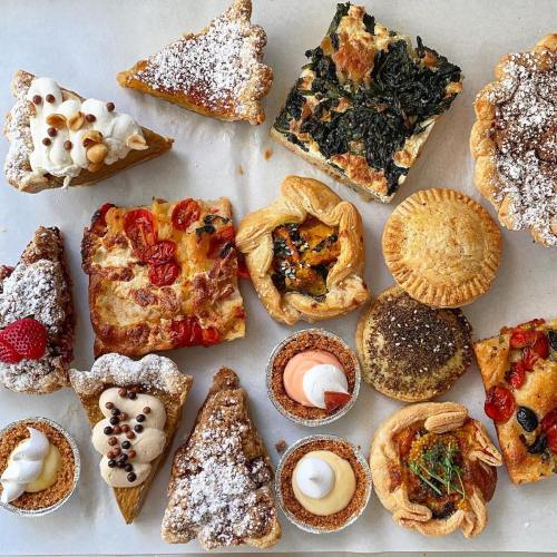 A variety of baked goods including pies, tarts, and pastries, arranged on a parchment-lined surface.