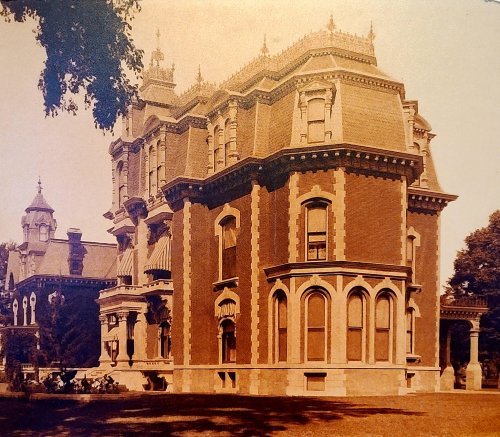 A historic mansion with ornate architecture, featuring a steep roof and decorative details, surrounded by trees.