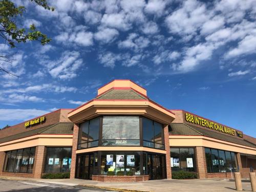 Exterior of 888 International Market, a brick building with large windows and a blue sky filled with clouds.