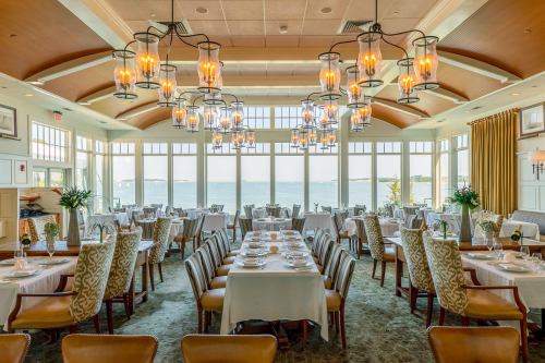 Elegant restaurant interior with large windows overlooking the water, featuring tables set for dining and stylish lighting.