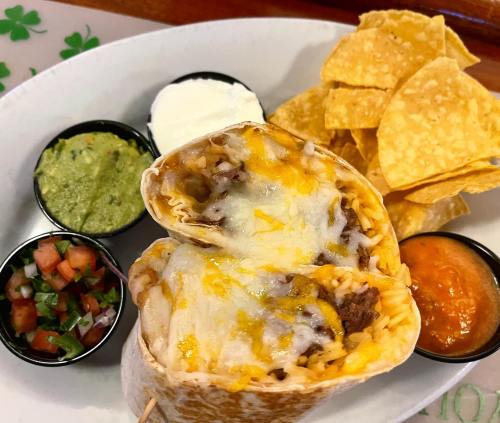 A close-up of a burrito filled with rice and cheese, served with guacamole, sour cream, salsa, and tortilla chips.