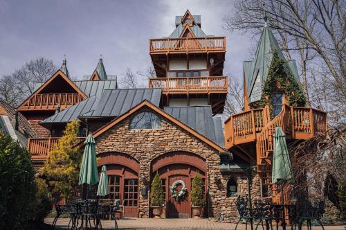 A charming stone building with a tall, ornate tower and balconies, surrounded by greenery and outdoor seating.