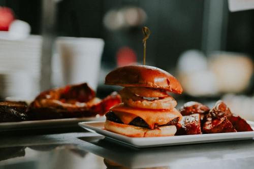 A stacked cheeseburger with two patties and melted cheese, served on a plate with crispy sides in a restaurant setting.