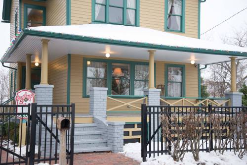 A charming yellow house with snow-covered steps and a black fence, decorated for the holidays.