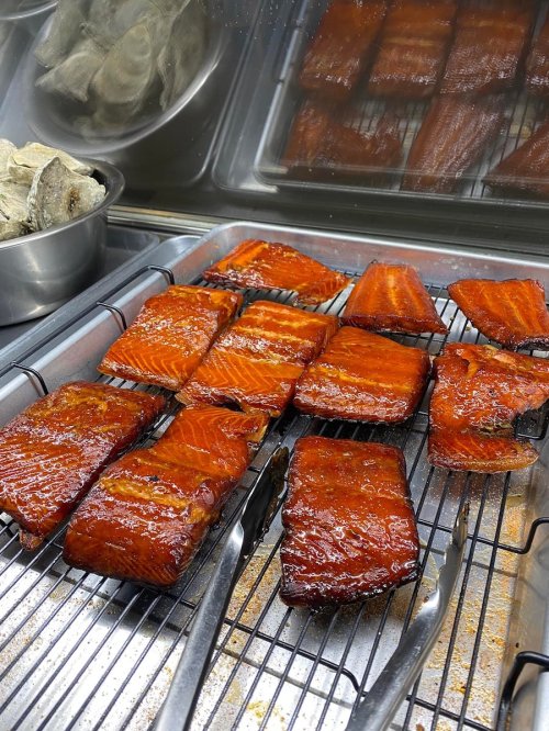 Grilled salmon fillets on a rack, with a side of oysters in a metal container.