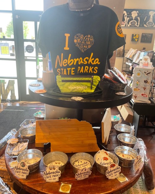 A display featuring a "I Love Nebraska State Parks" t-shirt and various merchandise in a gift shop.
