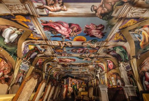 A lavishly decorated room with a ceiling featuring vibrant, classical murals and ornate furnishings.