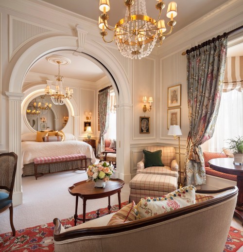 Luxurious hotel room featuring elegant decor, a cozy seating area, and a view of a beautifully styled bedroom.