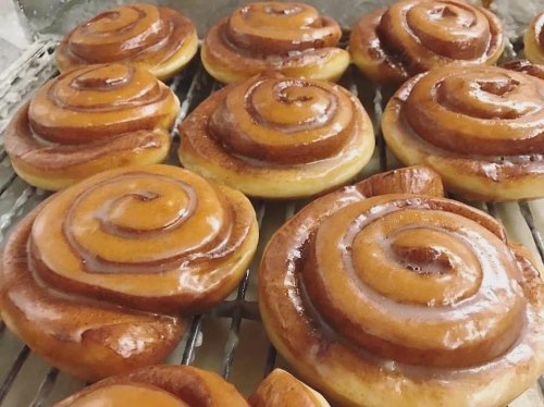 Freshly baked cinnamon rolls with glossy icing, arranged on a cooling rack.