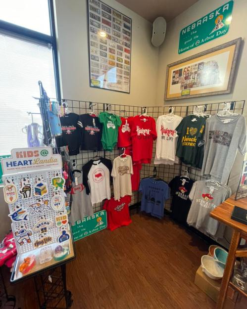 A display of various t-shirts and sweatshirts on a rack, featuring colorful designs and slogans, in a shop setting.