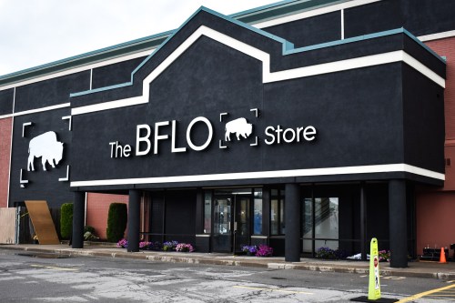 Exterior of The BFLO Store, featuring a black facade with white lettering and a buffalo logo, surrounded by flowers.