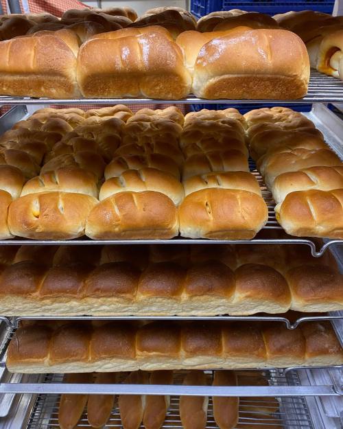 Freshly baked golden-brown bread rolls stacked on cooling racks.