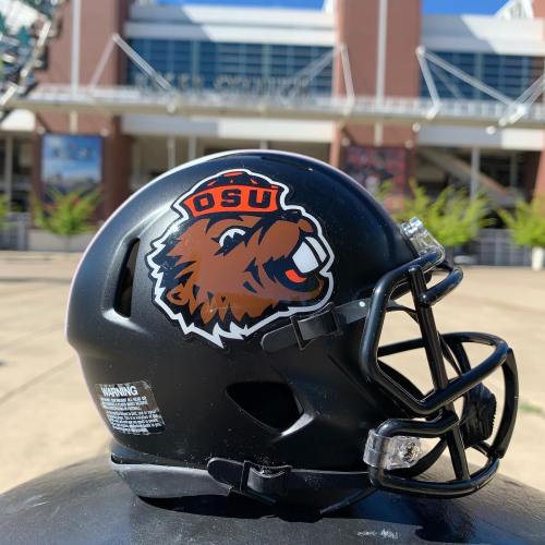 Black football helmet featuring the Oregon State University Beavers logo, displayed outdoors in front of a stadium.