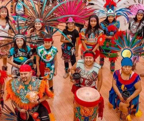 A vibrant group of dancers in traditional attire, featuring colorful feathered headdresses and drums, celebrating culture.