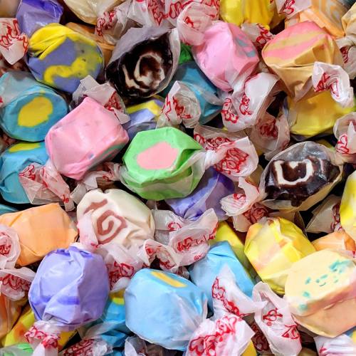 A colorful assortment of wrapped candies in various pastel shades and patterns, piled together.