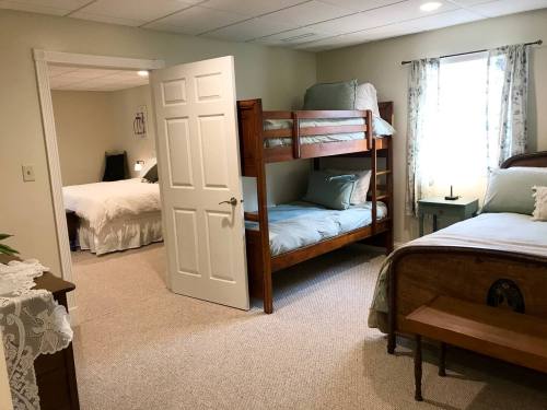 A cozy bedroom featuring a bunk bed and a separate bed, with soft lighting and neutral decor.