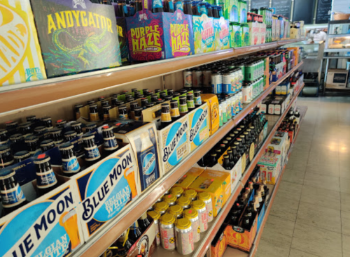A colorful display of various beer and beverage cans and bottles on shelves in a store.