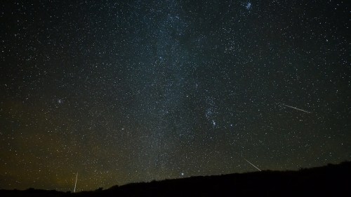A starry night sky filled with countless stars and a few shooting stars streaking across the dark expanse.