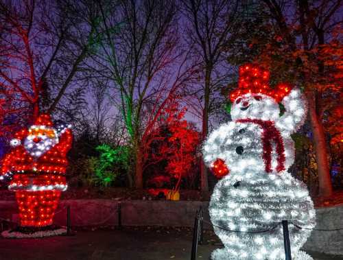 A festive scene featuring a lit snowman and Santa Claus, surrounded by colorful lights and trees at dusk.