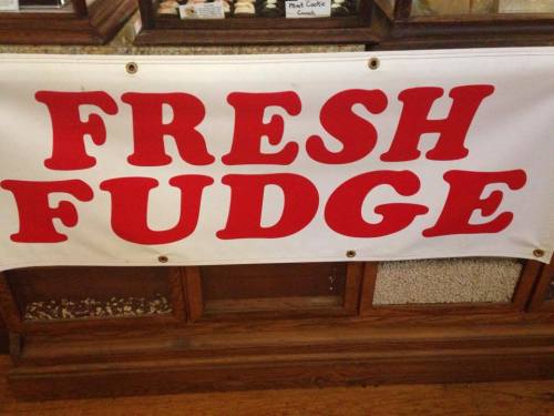 A large banner reading "FRESH FUDGE" in bold red letters on a white background, displayed in a shop.