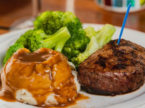 A plate featuring a grilled steak, mashed potatoes with gravy, and steamed broccoli.