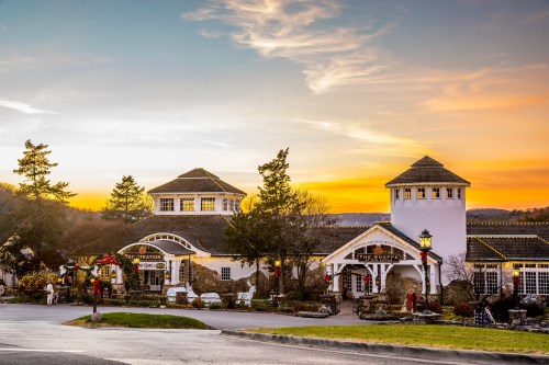 A charming building with towers, decorated for the holidays, set against a vibrant sunset sky.