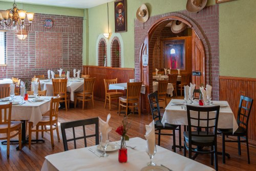 Cozy restaurant interior with wooden tables, chairs, and decorative elements, featuring a warm, inviting atmosphere.