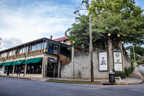A street view of a building with green awnings, stairs, and a sign for "Tropic City" on the side.