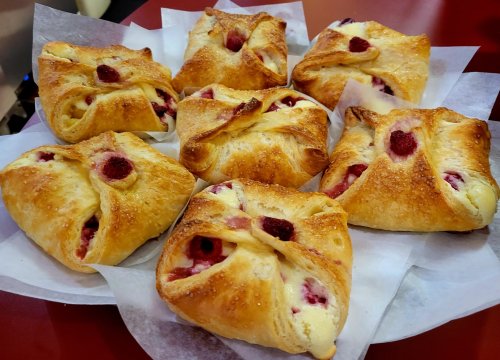 A platter of freshly baked pastries with raspberry filling, arranged neatly on parchment paper.