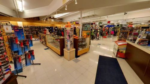 A spacious retail store interior filled with shelves of merchandise, display cases, and clothing racks.