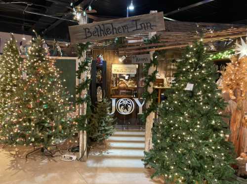 A festive display featuring a sign for "Bethlehem Inn" surrounded by decorated Christmas trees and holiday decor.