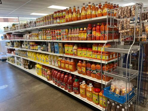 A grocery store aisle filled with various bottles of sauces, juices, and snacks on shelves.
