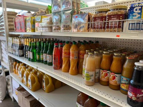 A grocery store shelf filled with various beverages, including juices, sodas, and jars of peanut butter.