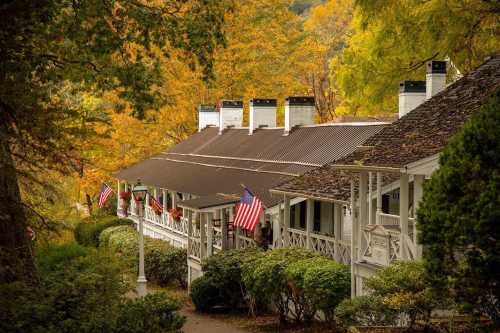 A charming lodge with American flags, surrounded by vibrant autumn foliage and lush greenery.