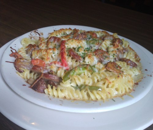 A plate of baked pasta with colorful vegetables and melted cheese, garnished with herbs.