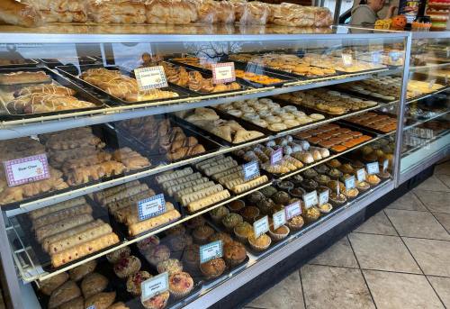 A display case filled with various baked goods, including pastries, cookies, and muffins, in a bakery.