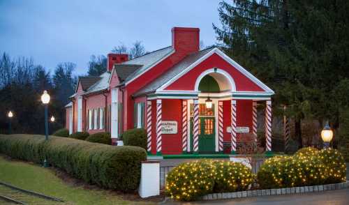 A festive red and white building with candy cane stripes, surrounded by greenery and twinkling lights.