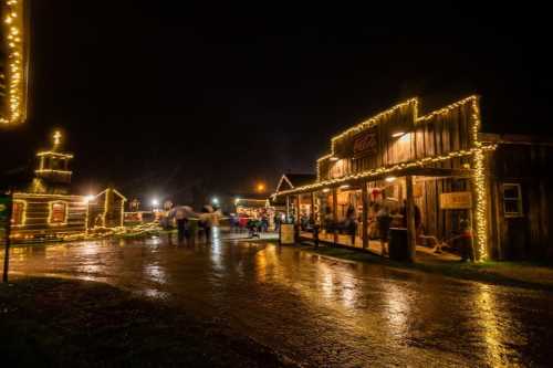 A festive night scene of a rustic town decorated with lights, reflecting on wet pavement, with people enjoying the atmosphere.