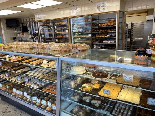 A bakery display case filled with various pastries, cakes, and bread, with shelves of baked goods in the background.
