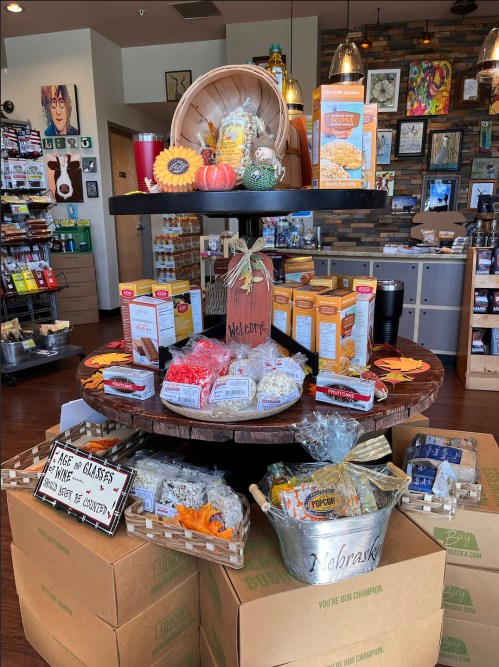 A display table in a store featuring various snacks, decorations, and a "Welcome" sign, surrounded by boxes.