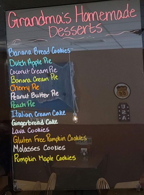 A mirror displays a colorful menu of homemade desserts, including pies, cookies, and cakes.