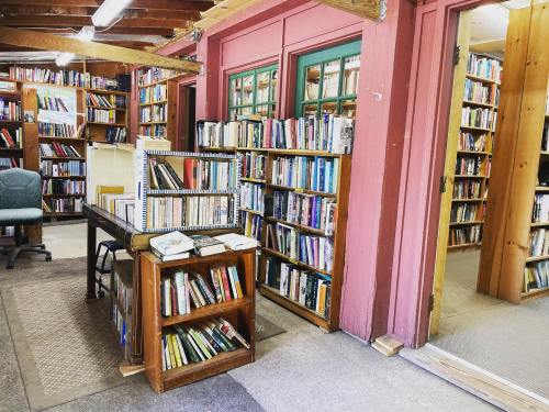 A cozy library interior with wooden shelves filled with books and a table in the center, inviting reading space.