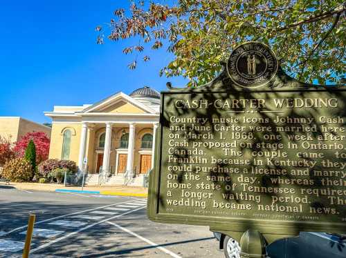 Sign commemorating the wedding of Johnny Cash and June Carter, with a historic building in the background.