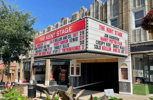 The Kent Stage marquee displays upcoming events and showtimes, with a vintage theater facade and surrounding greenery.