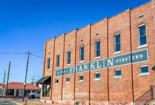 Historic brick building in downtown Franklin, featuring a large painted sign on the side against a clear blue sky.
